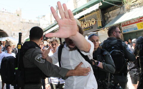 Police restrain a far-right activist from attacking a Times of Israel reporter in the Arab Quarter of the Old City of Jerusalem during clashes ahead of the annual Jerusalem Day Flag Parade, June 5, 2024. (Sam Sokol/Times of Israel)