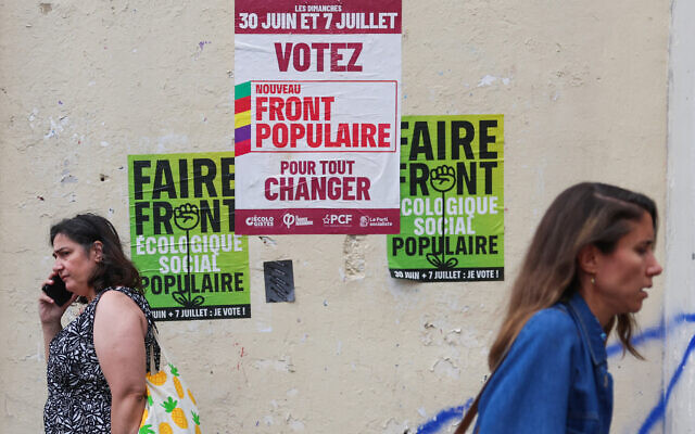 Two pedestrians walk past election posters of the left-wing Nouveau Front Populaire (New Popular Front - NFP) in Paris, on July 3, 2024, ahead of the second round of France's legislative elections. (Emmanuel Dunand/AFP)
